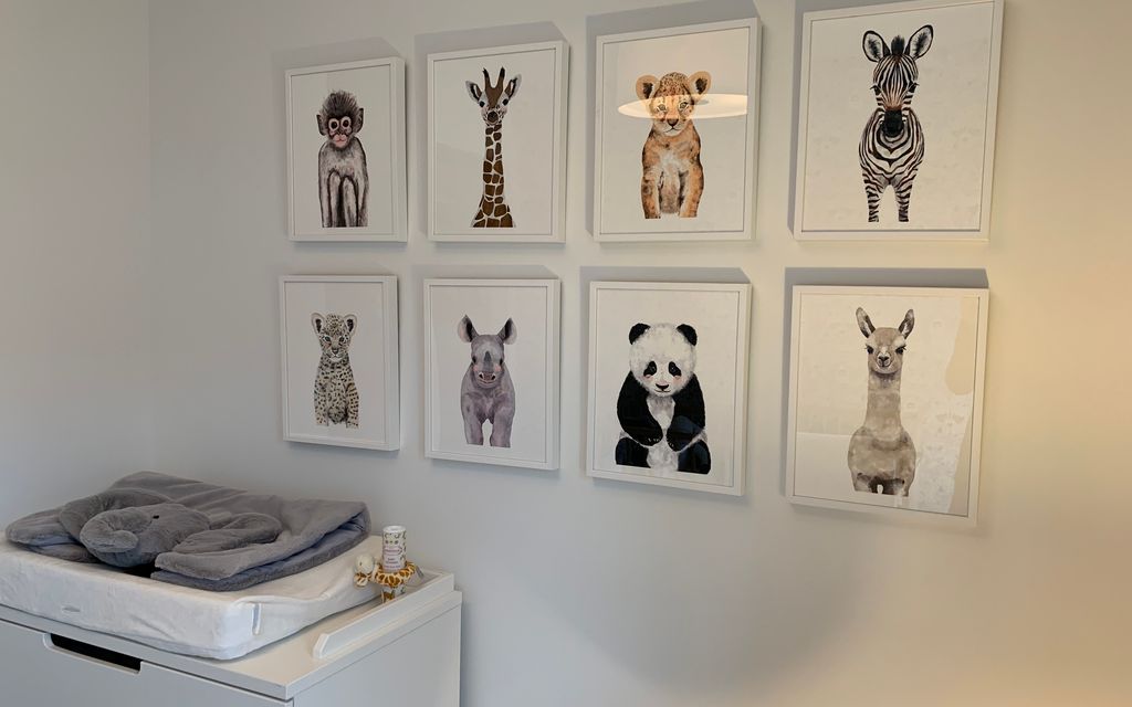 Cadres et affiches d'animaux au-dessus d'une commode de chambre de bébé