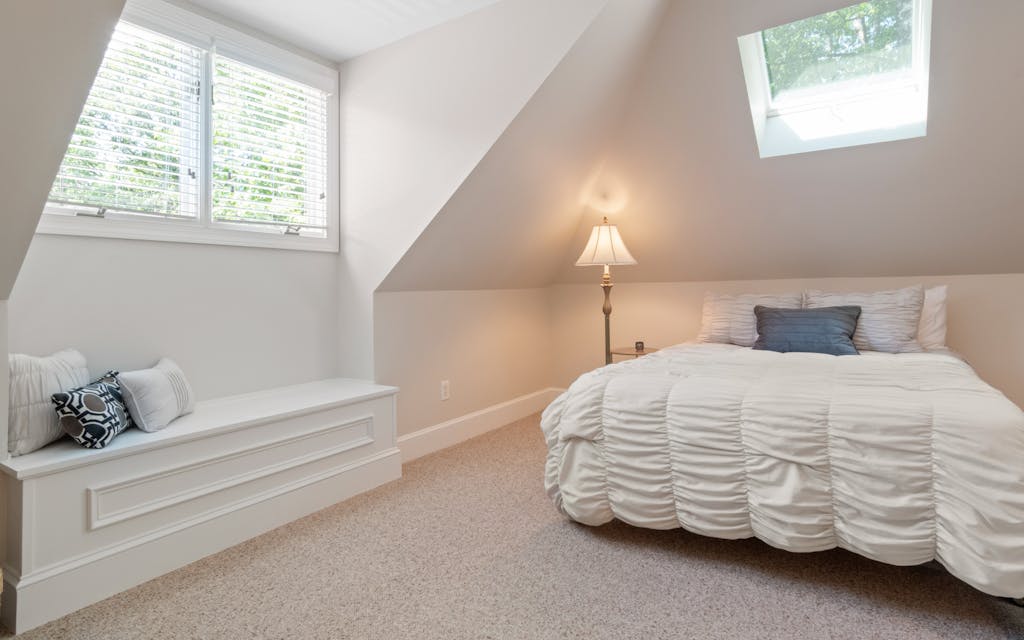 Chambre aménagée sous pente avec plafond mansardé et fenêtre de toit