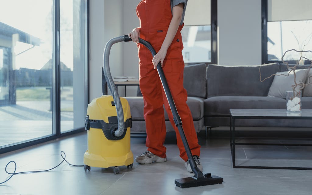 Aide-ménagère passant l'aspirateur dans un salon