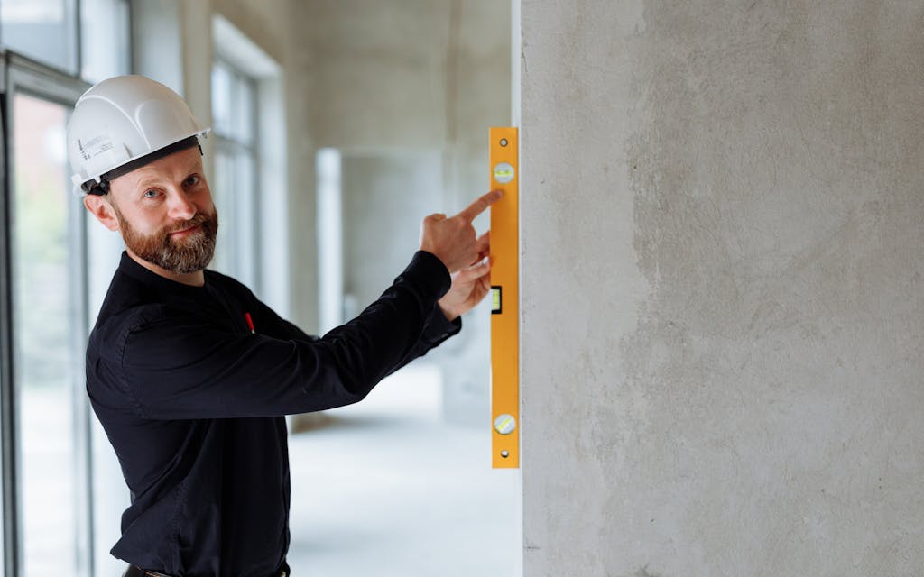 Artisan vérifiant l'aplomb d'un mur au niveau à bulle