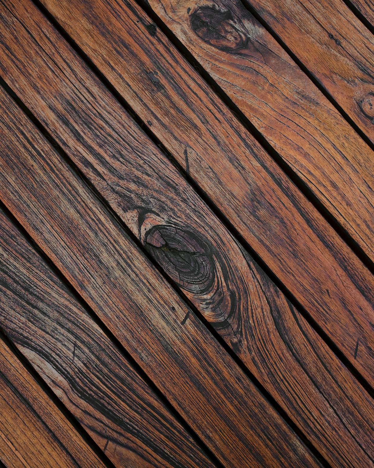 Pinceau appliquant de la lasure brune sur une planche de bois extérieur