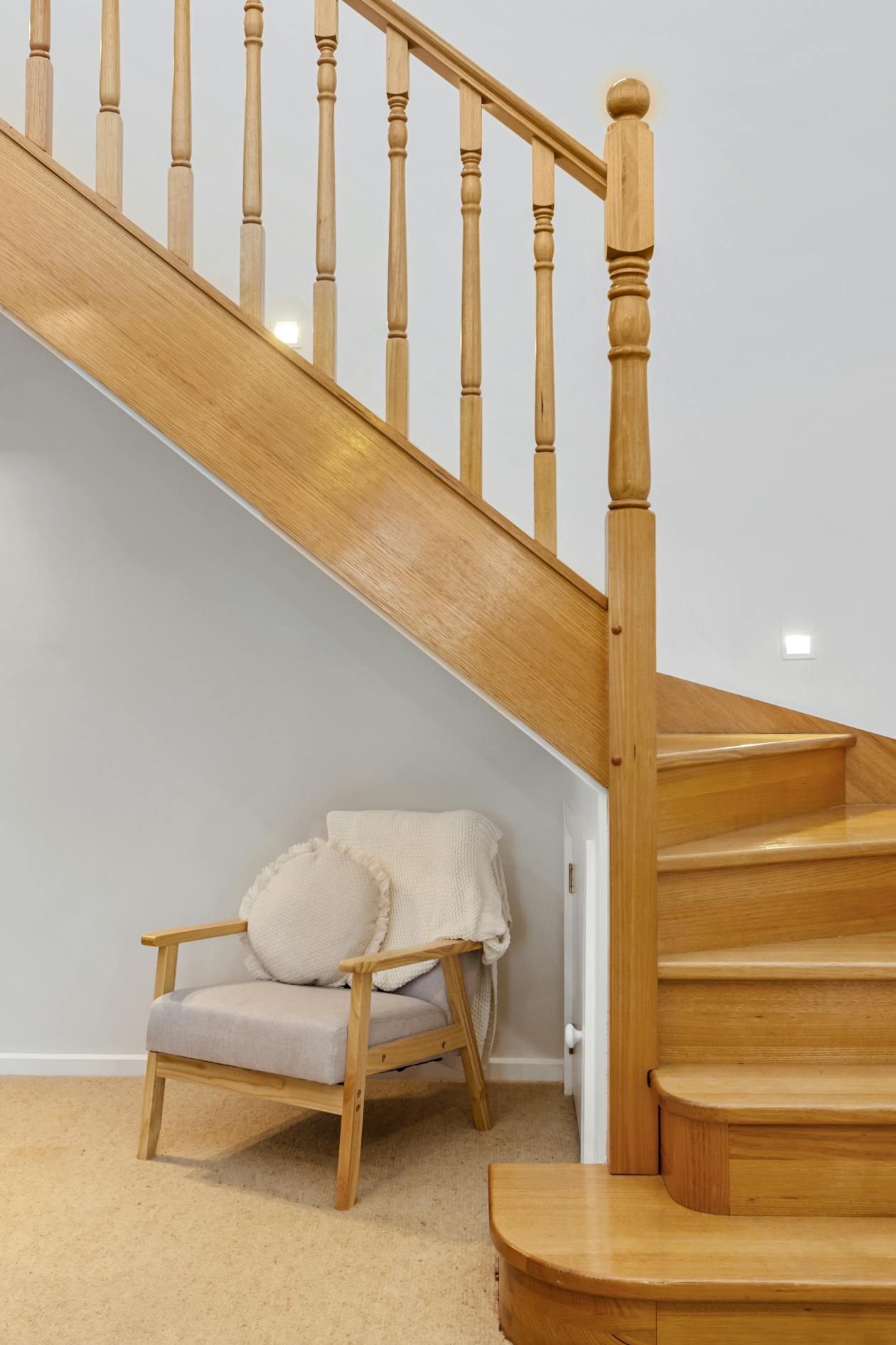 Placard aménagé sous un escalier avec étagères et baguettes de rangement