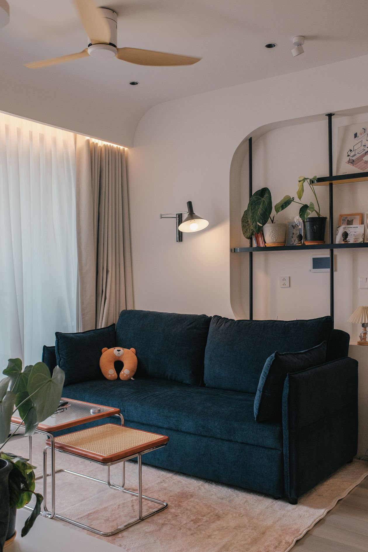 Salon cosy avec canapé beige, coussins texturés, bougie et lumière chaleureuse