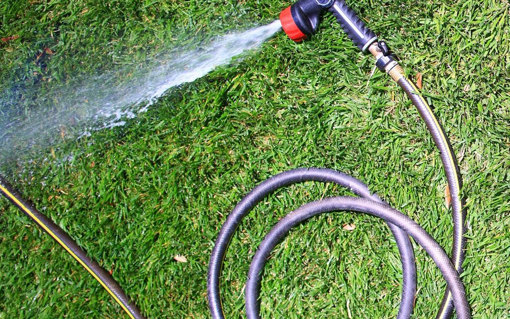 Tuyau d'arrosage vert enroulé dans un jardin