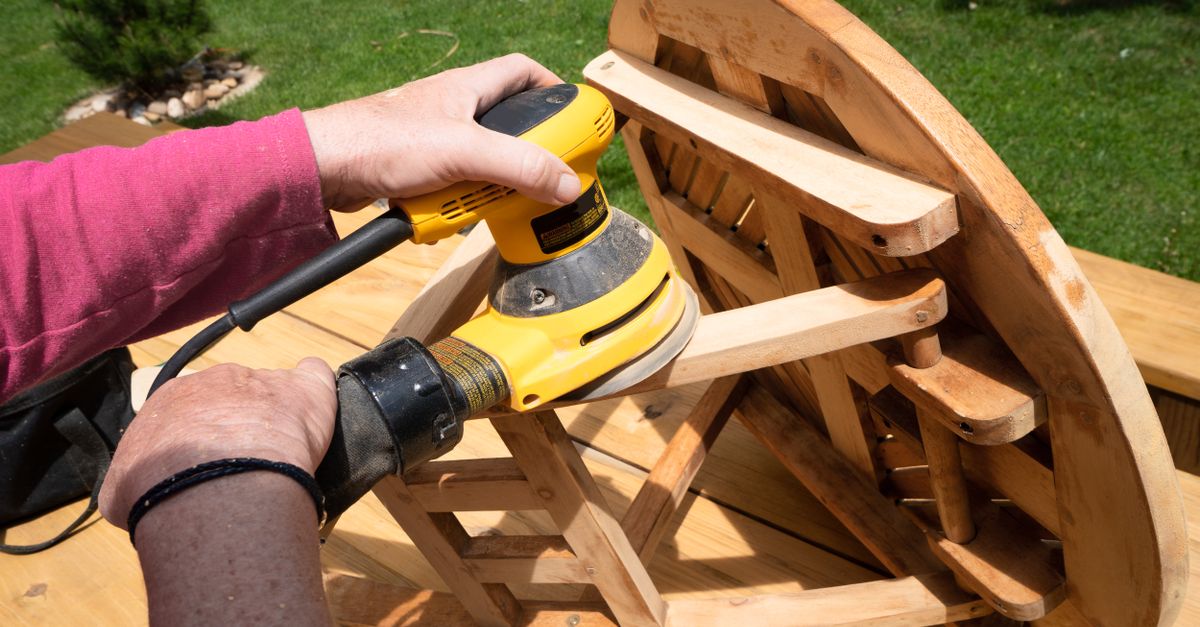 Ponceuse excentrique sur une planche en bois pendant une rénovation de meuble